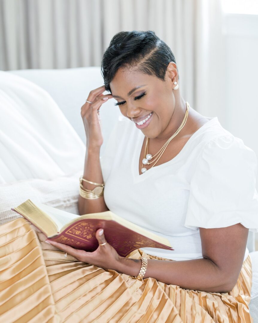 A woman sitting on the bed reading a book.