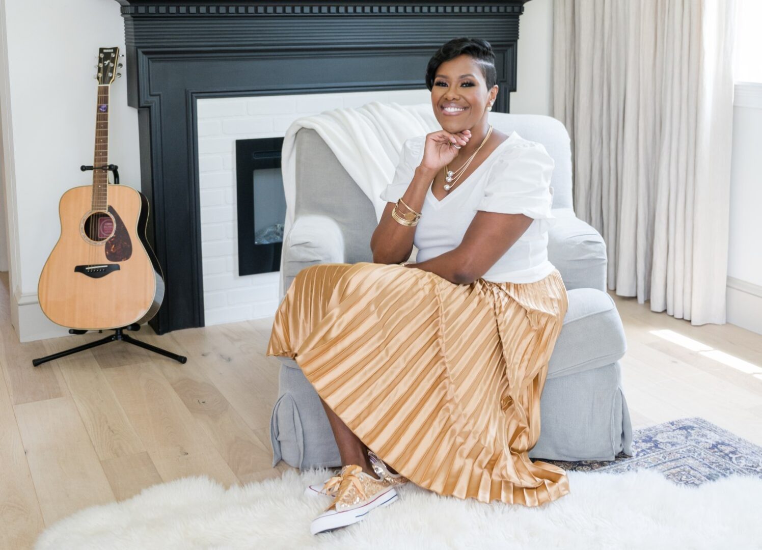 A woman sitting on top of a chair in front of a fireplace.